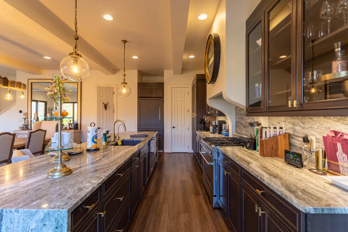 A closer look at the kitchen island highlights the granite countertops, stylish lighting, and stainless steel appliances. The scene suggests a space designed for preparing meals and hosting memorable gatherings, with a functional yet inviting layout.