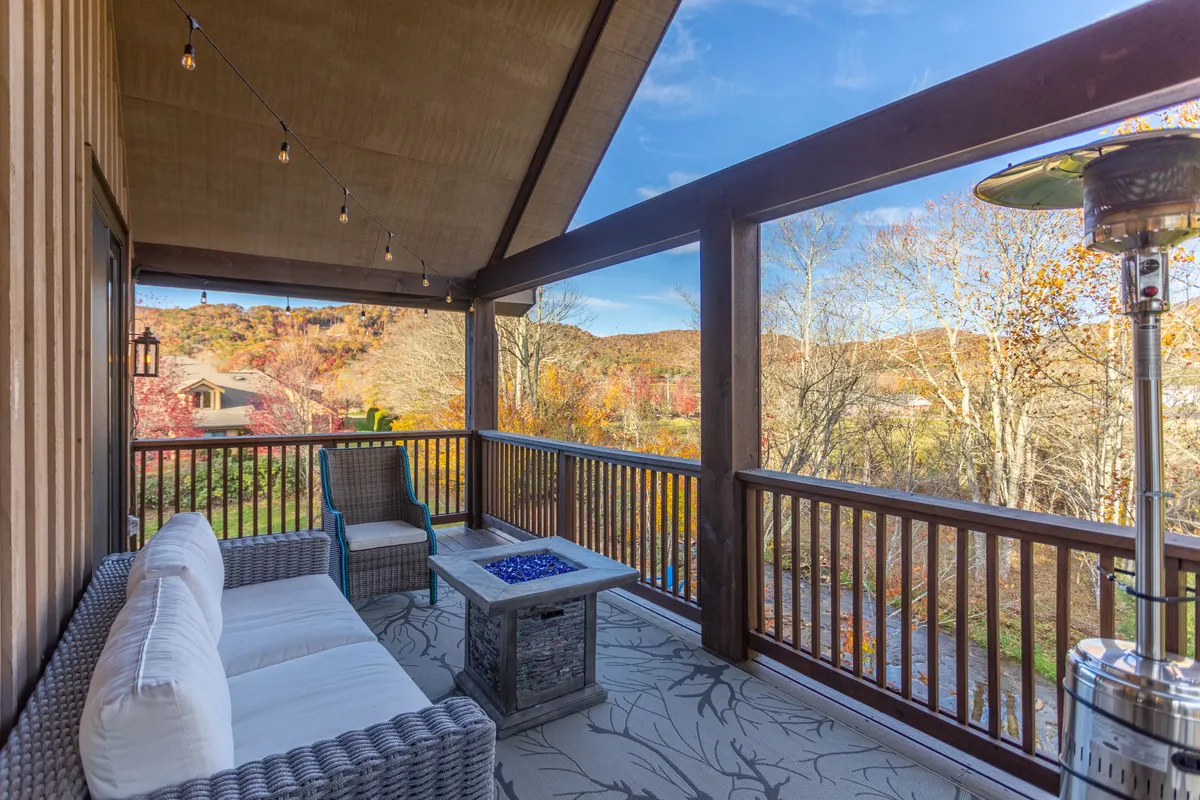 A seating area with plush wicker chairs and a fire pit table, offering panoramic views of the surrounding mountains and peaceful countryside. The setup is perfect for morning relaxation or evening stargazing.