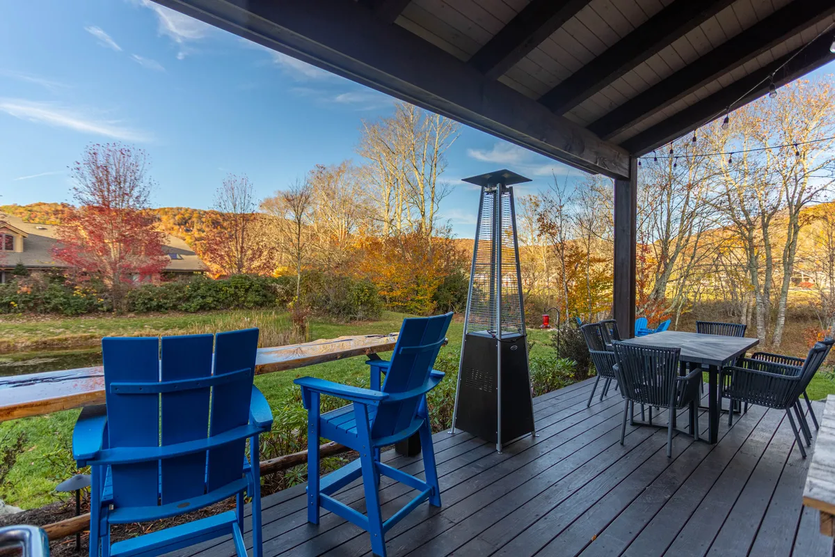 An inviting outdoor dining area featuring blue chairs, a welcoming table, and an outdoor heater, all set to take advantage of the natural surroundings. The setup hints at opportunities for al fresco dining, relaxed conversations at sunset, or cozy stargazing nights.